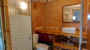 Een badkamer met toilet, douche, wastafel en spiegel.