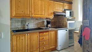 Een keuken met houten kastjes, een magnetron, een koffiezetapparaat en een vaatwasser.