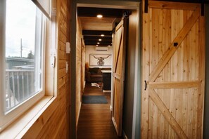 A narrow wooden hallway with a door on the right and a window on the left.