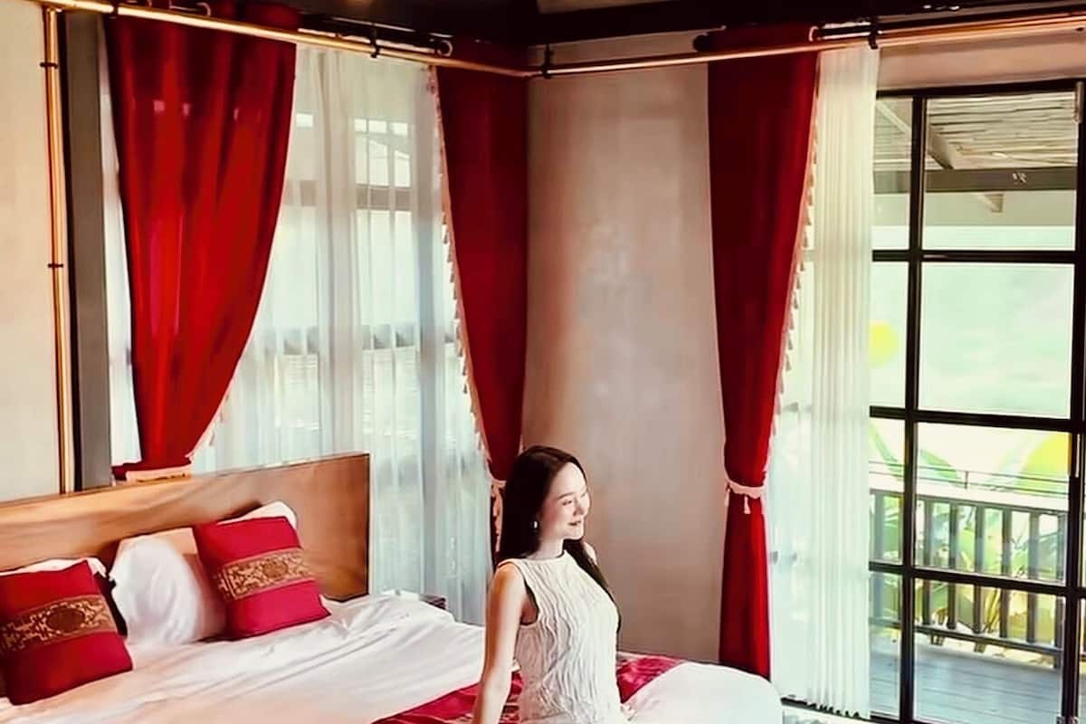 Un dormitorio con cama, cortinas rojas y vistas al exterior.