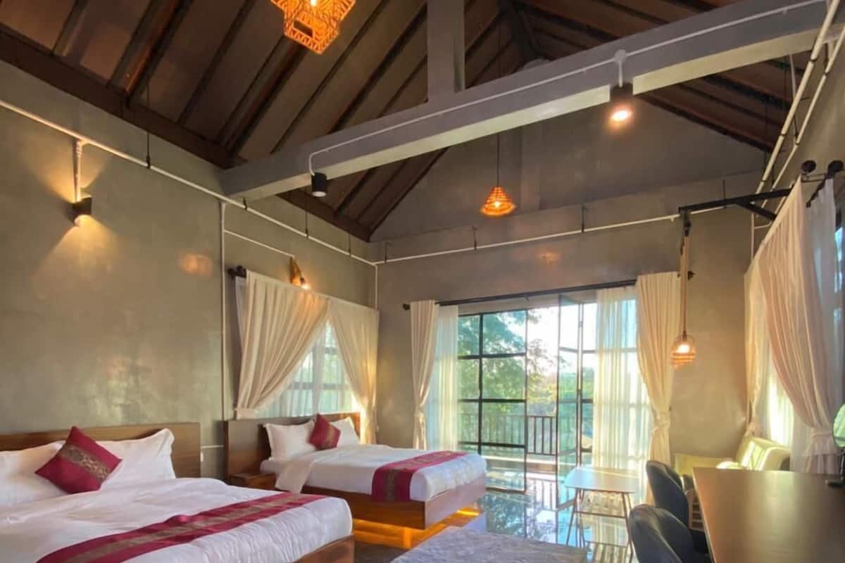 Una habitación amplia con dos camas, un comedor y ventanas grandes.