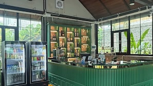 A bar area with a green counter, two refrigerators stocked with beverages, and a ceiling fan.