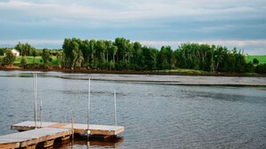 A calm lake with a wooden dock extending into the water, surrounded by a forested area.