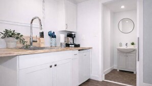 A modern kitchen with white cabinets, a wooden countertop, and a sink.