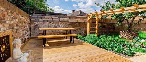 A wooden deck with benches, a statue, and a pergola.