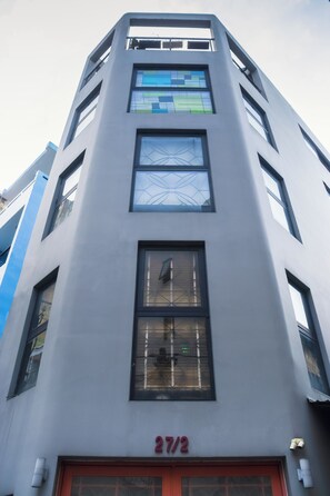 Ein modernes Gebäude mit flacher Fassade, zahlreichen Fenstern und einem gut sichtbaren Schild mit der Aufschrift '27/2', das die Adresse angibt.