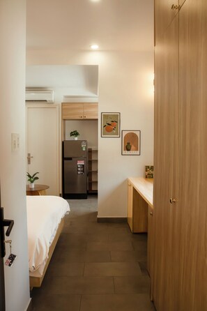 Ein Hotelzimmer mit einem Bett, einem kleinen Tisch, einem Kühlschrank und einer Holztür.
