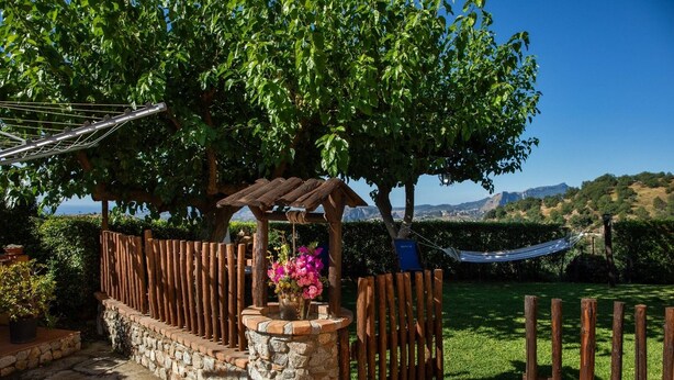 A garden with a wooden pergola, a hammock, and a stone wall. - 🦋the village villa 🦋 (Santa Caterina dello Ionio)