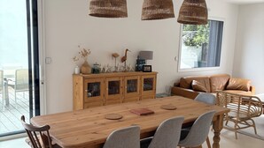 Ein Essbereich mit Holztisch, sechs Stühlen, Korbschirmleuchten und einem Holzschrank mit Dekoration.