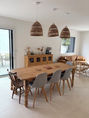 A dining area with a wooden table, six chairs, wicker pendant lights, and a wooden cabinet with decorative items. - Maison familiale à l'Ile Tudy - At the end of the street, it's the sea! (Île-Tudy)