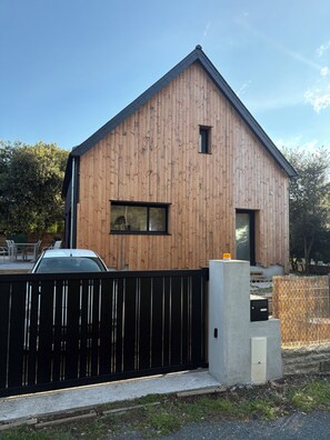 A modern wooden building with a black metal fence, a small window, and a concrete structure near the entrance. - Maison familiale à l'Ile Tudy - At the end of the street, it's the sea! (Île-Tudy)
