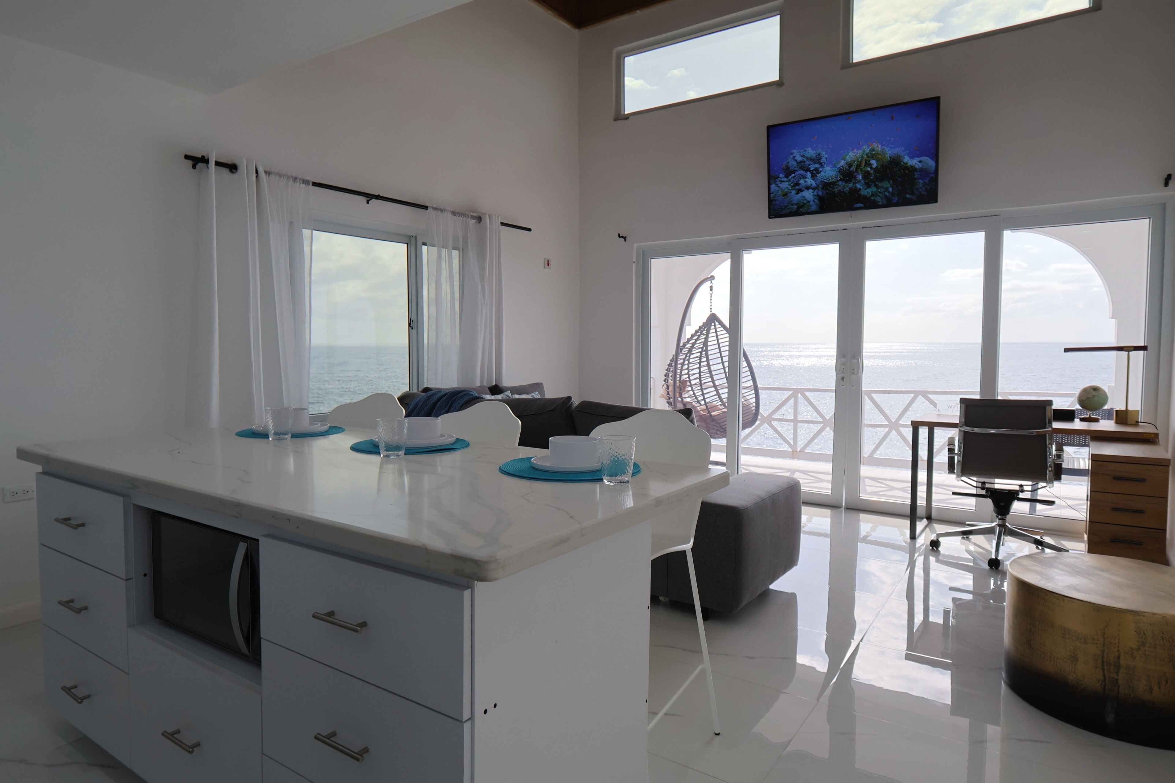 Una cucina moderna con una grande isola, un'area pranzo con vista e un televisore a parete.