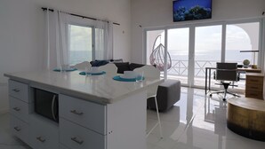 Een moderne keuken met een groot eiland, een eethoek met uitzicht en een aan de muur bevestigde televisie.