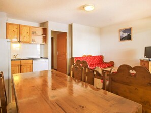 Ein Essbereich mit Holztisch und -stühlen, eine Küche mit Holzausstattung und ein rotes Sofa.