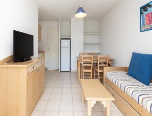 Un espacio habitable compacto con kitchenette, comedor, sofá y televisor.