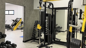 Un gimnasio con equipamiento de levantamiento de pesas, un espejo y una puerta que da a otra habitación.
