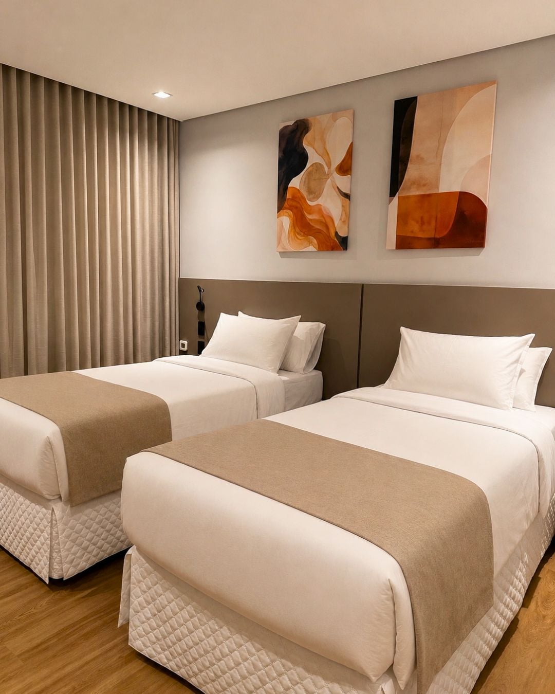 Quarto de hotel com duas camas, cabeceira e arte abstrata na parede.