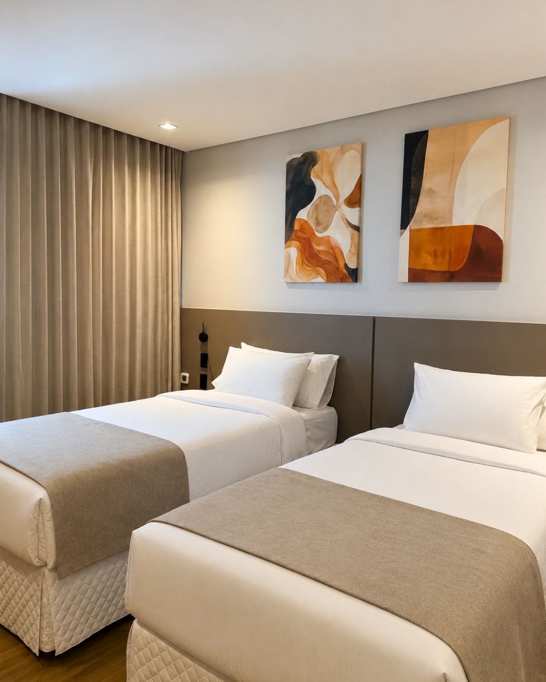 A hotel room with two beds, a large window with curtains, and abstract wall art.