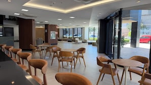 Un interior moderno con arreglos de asientos, una zona de recepción y grandes ventanales que ofrecen vistas al exterior.