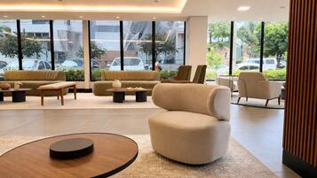 Um saguão moderno de hotel com um sofá, poltronas e uma mesa de centro.