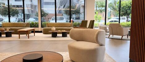 Un moderno vestíbulo de hotel con un sofá, sillones y una mesa de centro.