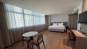 Una habitación de hotel con cama, escritorio, silla, mesa y televisor.