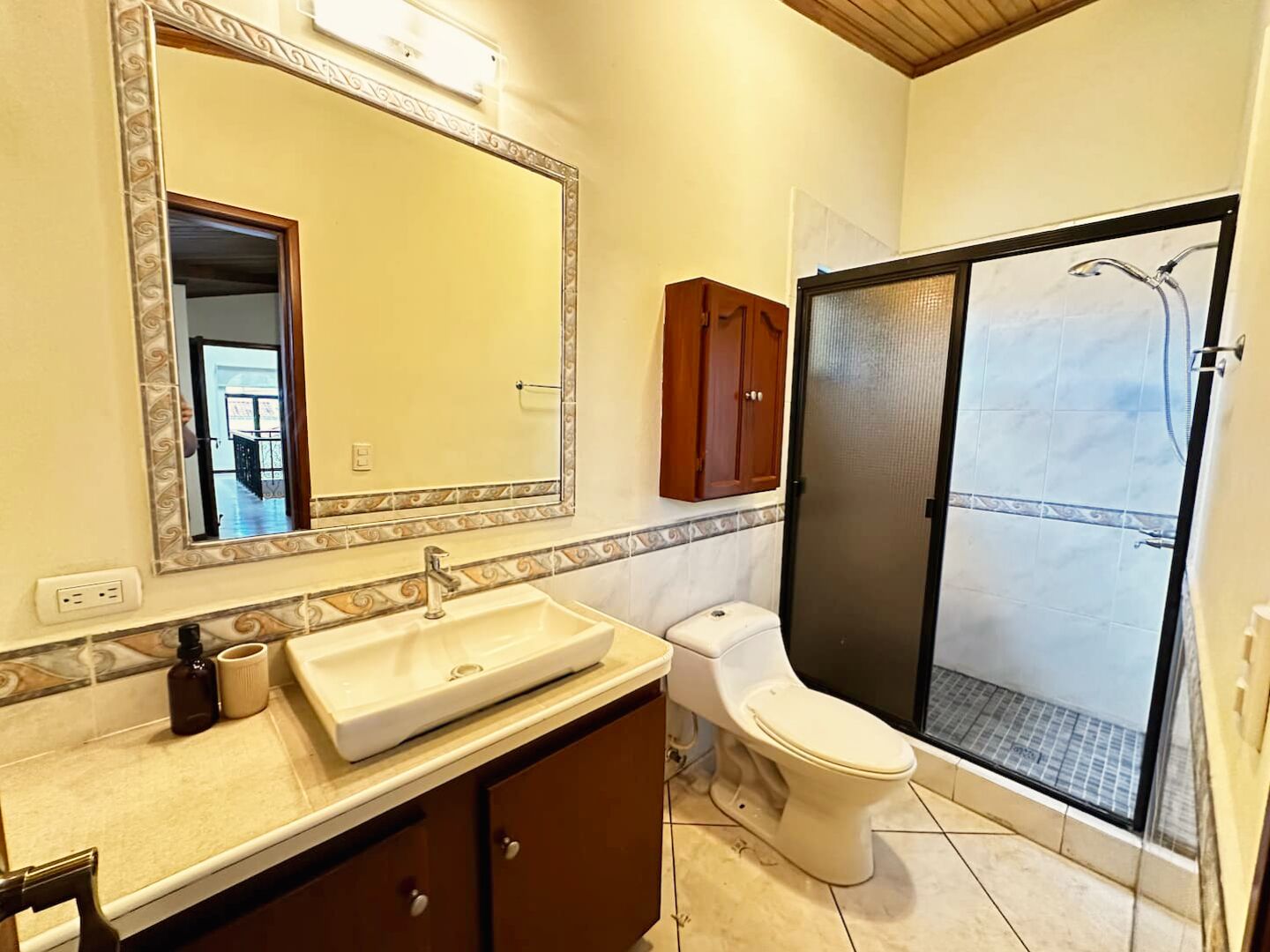 Een badkamer met een grote spiegel, een wastafel, een toilet, een kast en een douchecabine.