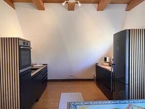 Eine kleine Küche mit Einbauofen, Kühlschrank und Holzschränken.