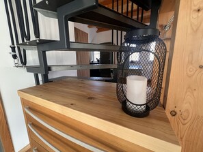 Ein Holztisch mit einer Metallregal-Konstruktion, einem schwarzen Netzlaterne und einer weißen Kerze.