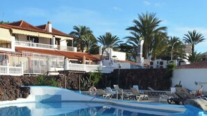 A clear swimming pool with lounge chairs, a lifebuoy, and a sign indicating the pool's depth. - Apartment in Playa de las Americas - Swimming pool, garden and excellent location (Arona)