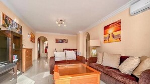 A living room with a wooden coffee table, a sofa, and a TV stand. - Apartment in Playa de las Americas - Swimming pool, garden and excellent location (Arona)