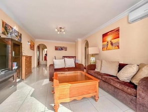 A living room with a wooden coffee table, a sofa, and a TV stand. - Apartment in Playa de las Americas - Swimming pool, garden and excellent location (Arona)