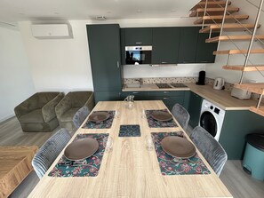 Une cuisine moderne avec un coin repas, des appareils électroménagers intégrés et un escalier en bois.
