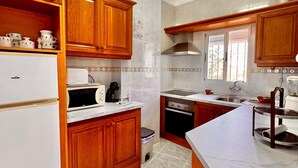 Una cocina con armarios de madera, un refrigerador, una estufa y un lavamanos.
