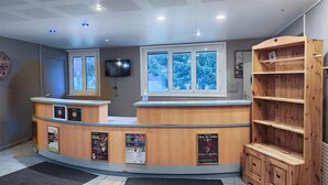 A reception desk with a television, posters, and a wooden shelf unit. - 2-bedroom Home in Monts Jura (Lelex)