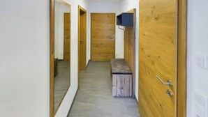 A hallway with wooden doors, a bench, and a mirror.
