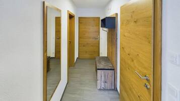 A hallway with wooden doors, a bench, and a mirror.