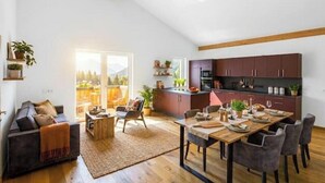A modern living room with a sofa, coffee table, and dining table set for four.