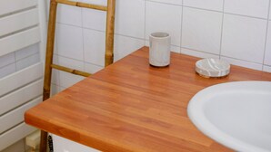 Ein Badezimmer mit einem Holzmöbelkorpus, einem weißen Waschbecken und einer Bambusleiter.