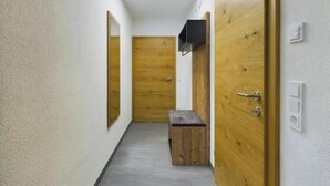 A hallway with wooden doors, a bench, and a ceiling light. - Alpenglühen Lodge Lechtal - Stylish vacation apartment with mountain views (Stockach)