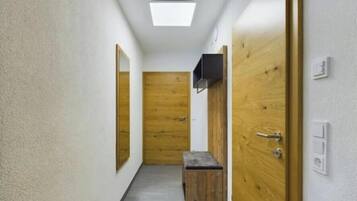 A hallway with wooden doors, a bench, and a ceiling light.