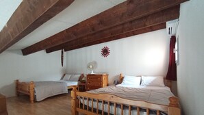 A bedroom with two wooden beds, a wooden dresser, a fan, and a wall-mounted decorative item. - Bright apartment for 6 people, near the sea (Agde)