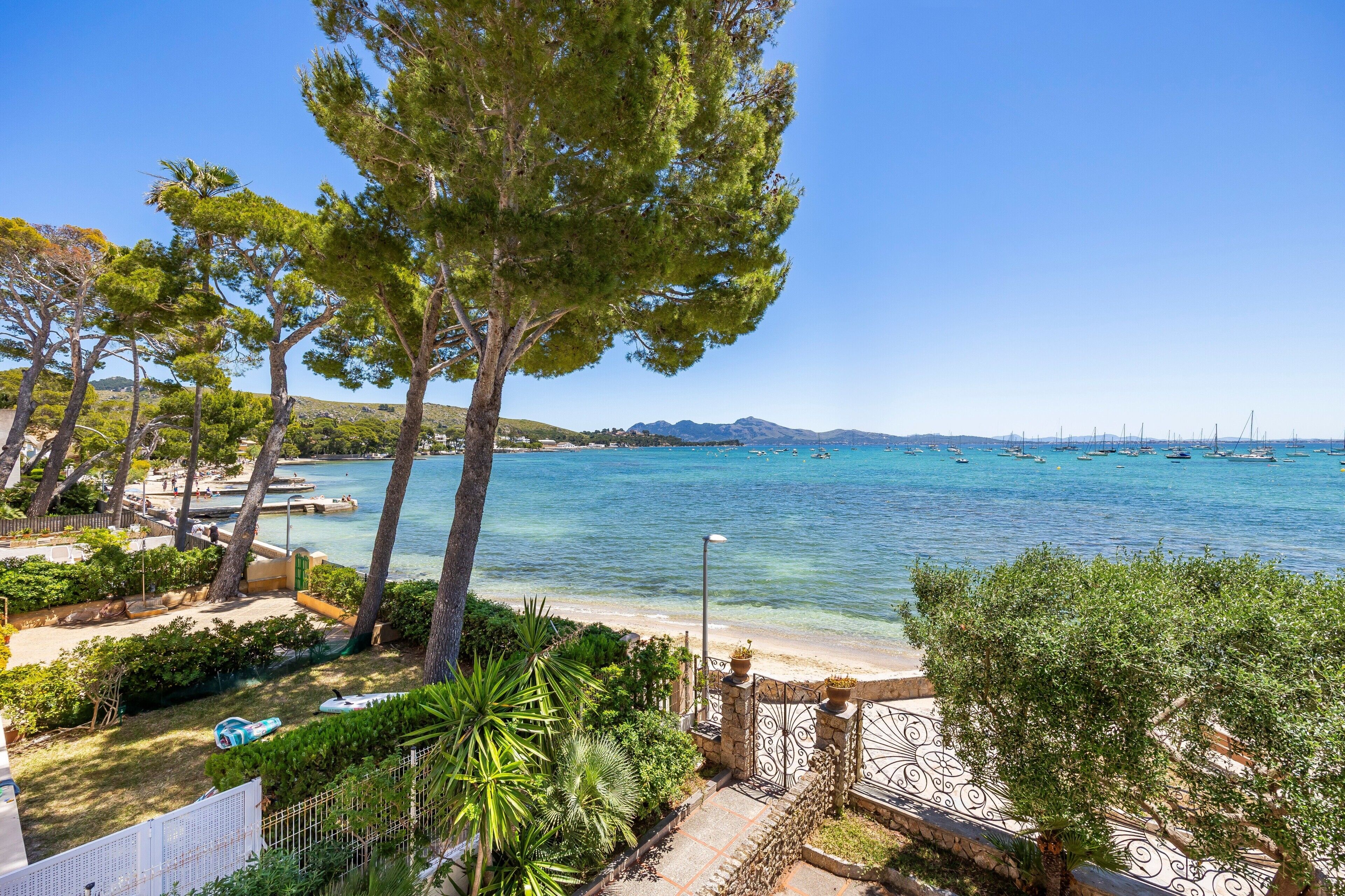 A coastal view with clear blue water, boats, and a beach.