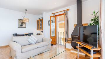 Een woonkamer met een bank, tv en open haard.