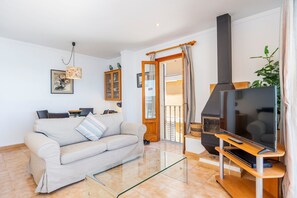 A living room with a sofa, TV, and fireplace. - 'Voramar 85' Apartment with Sea Views, Wi-Fi, and Air Conditioning (Port de Pollença)