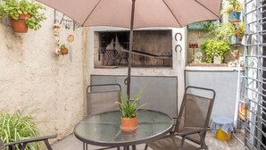 A patio with a round glass table, two chairs, a large umbrella, and a brick oven. - House in Pocitos, near the stadium and the promenade (Montevideo)
