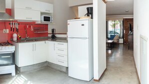 A compact kitchen with white cabinets, a gas stove, a microwave, and a refrigerator. - House in Pocitos, near the stadium and the promenade (Montevideo)