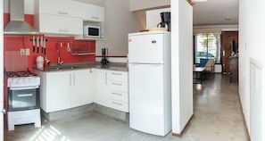 A compact kitchen with white cabinets, a gas stove, a microwave, and a refrigerator. - House in Pocitos, near the stadium and the promenade (Montevideo)