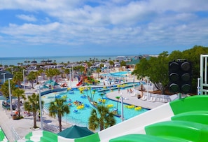 Ein Wasserpark mit mehreren Pools und Wasserrutschen, umgeben von Palmen und Blick auf den Strand.