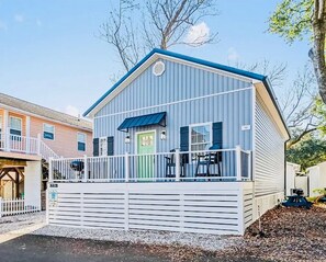 A single-story building with a blue roof and white exterior, featuring a front porch with a railing and a green door. - Southard Shores (Myrtle Beach)